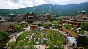 un groupe de personnes dans un parc devant un complexe hôtelier dans l'établissement 411 Spruce Peak Stowe Mountain Resort New Treehouse unit Ski in Ski out 4 bed sleeps 12, à Stowe Mountain