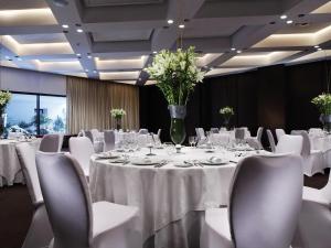 a conference room with white tables and chairs and vases with flowers at Mövenpick Hotel Gammarth Tunis in Gammarth +201 photos