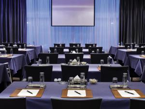 uma sala de conferências com mesas e cadeiras e uma tela em Mövenpick Hotel Al Khobar em Al Khobar