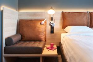 Zimmer mit einem Bett und einem Stuhl mit einer Lampe in der Unterkunft Moxy Birmingham NEC in Bickenhill