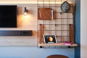 Ein Zimmer mit einem Fernseher und einem Laptop auf einem Regal. in der Unterkunft Moxy Birmingham NEC in Bickenhill