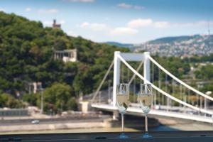 two wine glasses sitting on a table in front of a bridge at Flat with Unforgettable View in Budapest