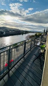 eine Holzterrasse mit Flussblick in der Unterkunft Vū by the Bridge, Inverness City Centre in Inverness