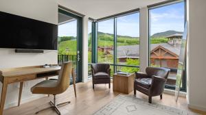 un bureau à domicile avec un bureau, des chaises et de grandes fenêtres dans l'établissement 420 Lodge At Spruce Peak New Treehouse Unit 3 bed Sleeps 10, à Stowe