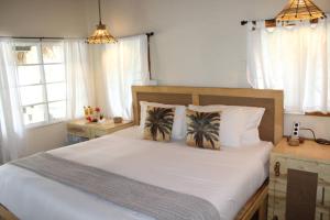 a bedroom with a large bed with white sheets and pillows at Caribbean Beach Cabanas in Placencia Village