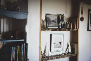 a book shelf with a mirror and some books at Cowes View Seaside beach cottage, in Hill Head