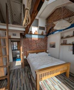 a bedroom with a bed and a brick wall at Cowes View Seaside beach cottage, in Hill Head