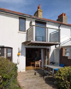 a white house with a patio and a table at Cowes View Seaside beach cottage, in Hill Head +14 photos