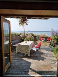 a patio with a table and chairs and the ocean at Cowes View Seaside beach cottage, in Hill Head