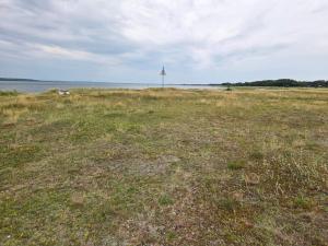 un champ d'herbe avec un phare au loin dans l'établissement Pool Paradise in Helberskov - By Traum Ferienwohnungen, à Helberskov 25 autres photos