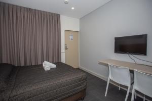 ein Hotelzimmer mit Bett, Schreibtisch und Fernseher in der Unterkunft Westside Motor Inn in Sydney