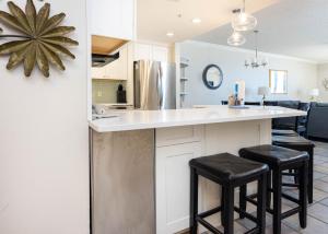 a kitchen with white cabinets and black stools at Phoenix X 609 condo in Orange Beach