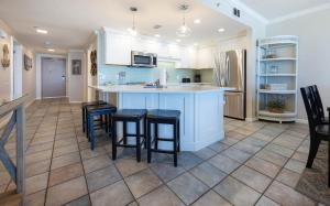a kitchen with white cabinets and a island with bar stools at Phoenix X 609 condo in Orange Beach
