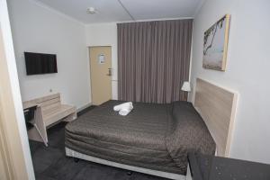 ein Hotelzimmer mit Bett und Schreibtisch in der Unterkunft Westside Motor Inn in Sydney