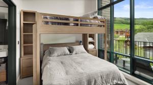 une chambre avec un lit superposé et une grande fenêtre dans l'établissement Stowe Mt Resort Spruce Peak 4 Bed Treehouse Condo By Stowe Mountain Rentals, à Stowe