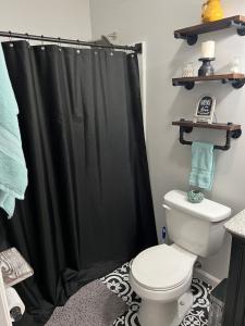 La salle de bains est pourvue d'un rideau de douche noir et de toilettes. dans l'établissement Cozy Studio Apartment, à Montgomery