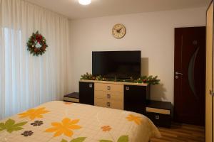 a bedroom with a tv and a bed and a dresser at Noah Apartment in Craiova