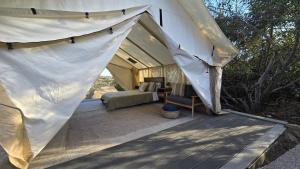 Zelt mit einem Bett und einem Stuhl auf einer Terrasse in der Unterkunft Cozy Mountain View Glamping Tent in De Luz Heights