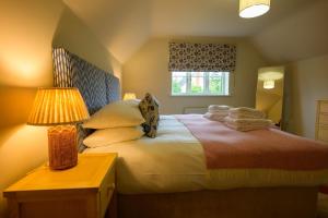 une chambre avec un lit avec une lampe et une fenêtre dans l'établissement Cragie Cottage- Beautiful Cotswold stone retreat, à Kemerton