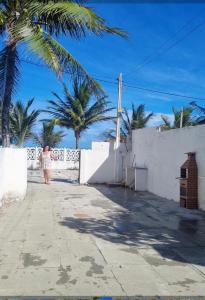une femme marchant sur un trottoir le long d'un mur blanc orné de palmiers dans l'établissement Casabeiramaritamaracá, à Itamaracá