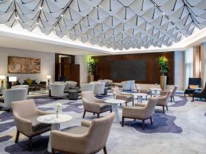 麦加Movenpick Hotel & Residences Hajar Tower Makkah的酒店大堂配有桌椅和投影屏幕