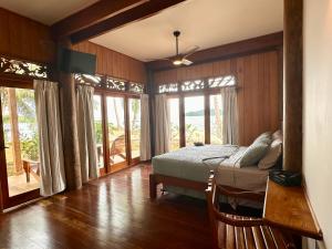 ein Schlafzimmer mit einem Bett und ein Zimmer mit Fenstern in der Unterkunft Bocas Beachfront Lodge Spacious Corner King Suite Ocean View Sand Level in Bocas del Toro