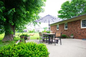 a patio with a table and chairs and an umbrella at Hidden Gem Farm Homestead Sleeps 12 &Fresh Produce in Spring Hill