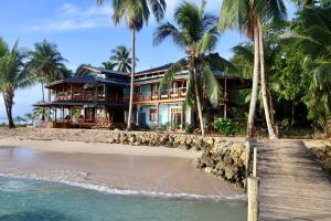 ein Haus an einem Strand mit Palmen in der Unterkunft Bocas Beachfront Lodge Spacious Corner King Suite Ocean View Sand Level in Bocas del Toro