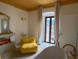 a bathroom with a yellow chair and a fireplace at La Trita Dimore di Charme in Bussi sul Tirino