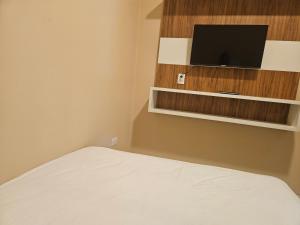 a bedroom with a bed and a tv on the wall at Urban Center Apartamentos in Salto del Guairá
