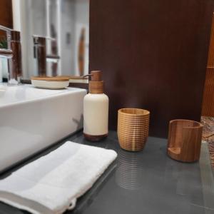 eine Badezimmerablage mit einer Flasche Seife und zwei Tassen in der Unterkunft Spacious 2BR near Odivelas Metro with Balcony in Odivelas + 12 Fotos