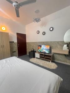 MawāliḩLuxury Rooms in Al Mouj Street - Excellent Location غرف فندقية راقية في شارع الموج - موقع مميز的一间卧室，里面有一张床和一台平板电视