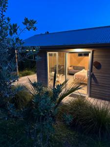 a house with a patio with a bed in it at One O One Cabins, Waiheke Island in Oneroa +8 photos