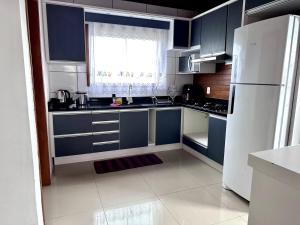 a kitchen with blue cabinets and a white refrigerator at Casa Guaruja 1 in Lages +11 photos