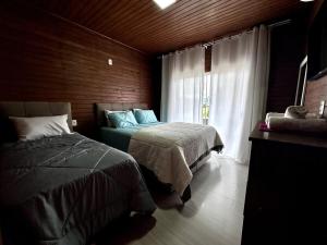 une chambre avec deux lits et une fenêtre dans l'établissement House Guarujá 02 em Lages SC próximo ao Shopping, à Lages