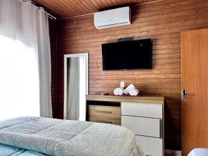 une chambre avec un lit et une télévision à écran plat dans l'établissement House Guarujá 02 em Lages SC próximo ao Shopping, à Lages