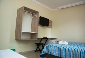 a bedroom with a bed and a tv and a chair at Pousada Cabo Branco in João Pessoa