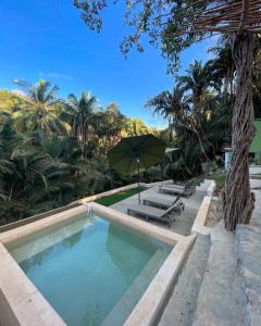 een zwembad met een parasol, stoelen en palmbomen bij Cupi Glamping in San Francisco