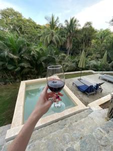a person holding a glass of wine in front of a pool at Cupi Glamping in San Francisco