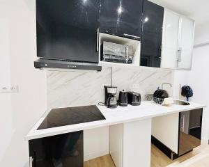 une cuisine avec un comptoir blanc et des armoires noires dans l'établissement Élégant studio rénové Confort et tranquillité, à Saint-Quentin