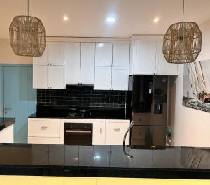 eine Küche mit weißen Schränken und einem schwarzen Kühlschrank in der Unterkunft Casa Betty 