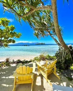 zwei gelbe Stühle an einem Strand mit Blick auf das Meer in der Unterkunft Marū Beach House in Afareaitu