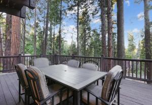 a wooden table and chairs on a deck with trees at Boss's Cabin - Boss-level views, zero stress! in Shaver Lake