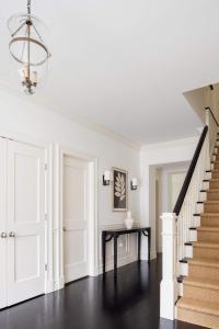 a white hallway with a black table and stairs at Oceanstone by Rove Villa w Pool & Beach Access in Southampton