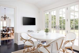 a white dining room with a white table and chairs at Oceanstone by Rove Villa w Pool & Beach Access in Southampton