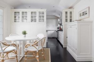 a white kitchen with a white table and chairs at Oceanstone by Rove Villa w Pool & Beach Access in Southampton +43 photos