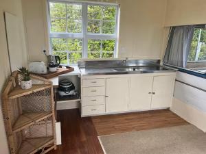 eine Küche mit Spüle und Fenster in der Unterkunft Simple Cabin, Kuaotunu - Peaceful, Affordable Stay in Kuaotunu