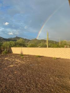een regenboog in de lucht over een stenen hek bij Dove Mountain Gem! in Marana