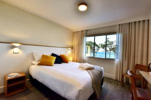 a hotel room with a large bed and a window at Lufra Beachside Hotel in Eaglehawk Neck