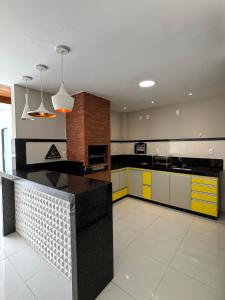 une cuisine avec des armoires jaunes et blanches et un comptoir noir dans l'établissement Apartamento Centro Guriri 3 Quartos, à São Mateus